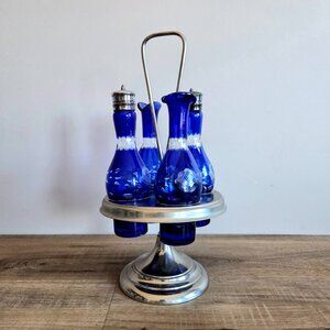 Vintage cobalt blue cut to clear glass condiment set on metal stand.